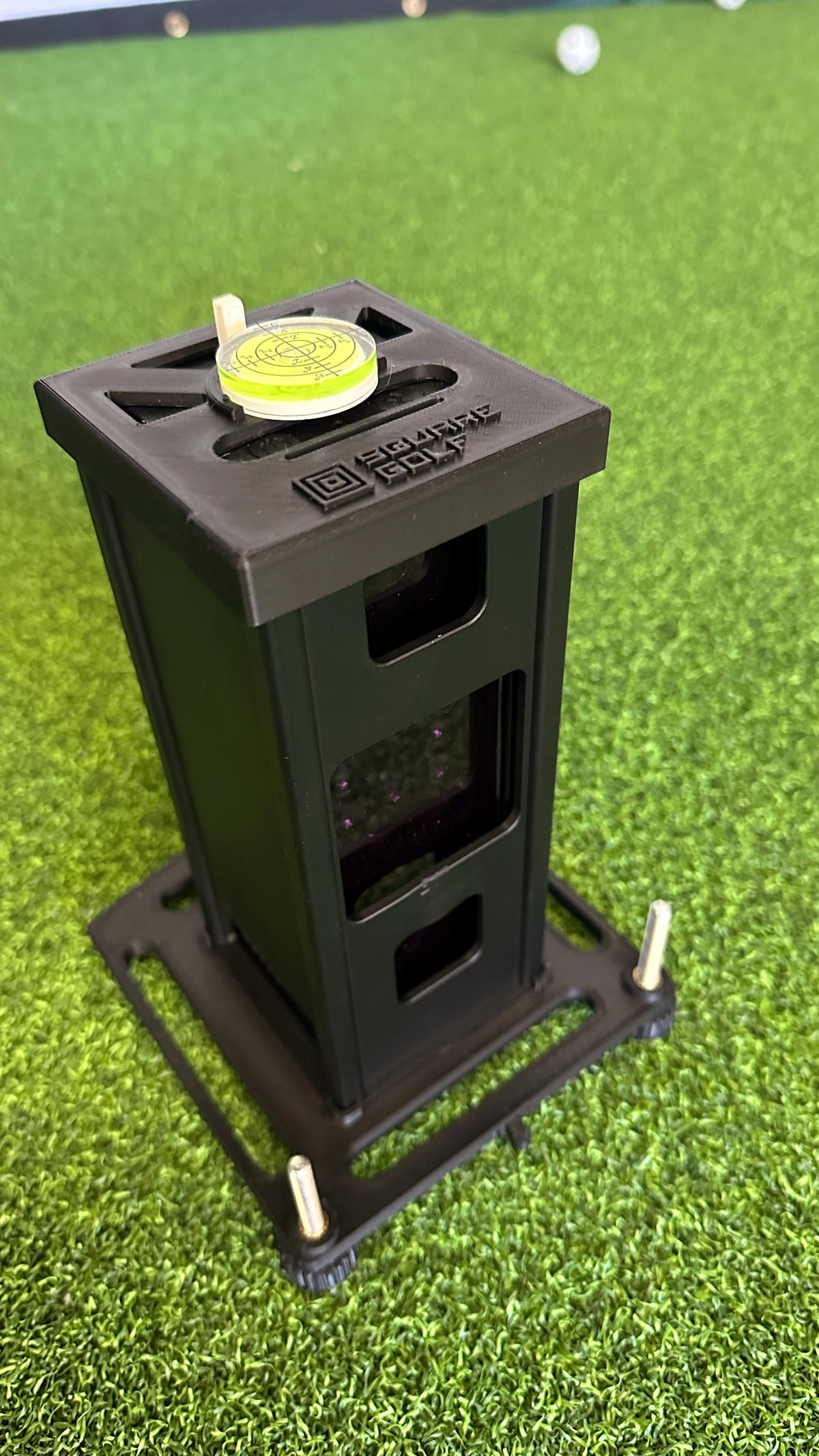 Original Square Golf metal case shown in an adjustable leveling base with bubble level