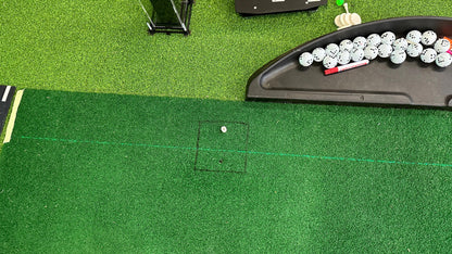 Golf hitting mat with marked ball position and green laser alignment line; Square Golf case in the background