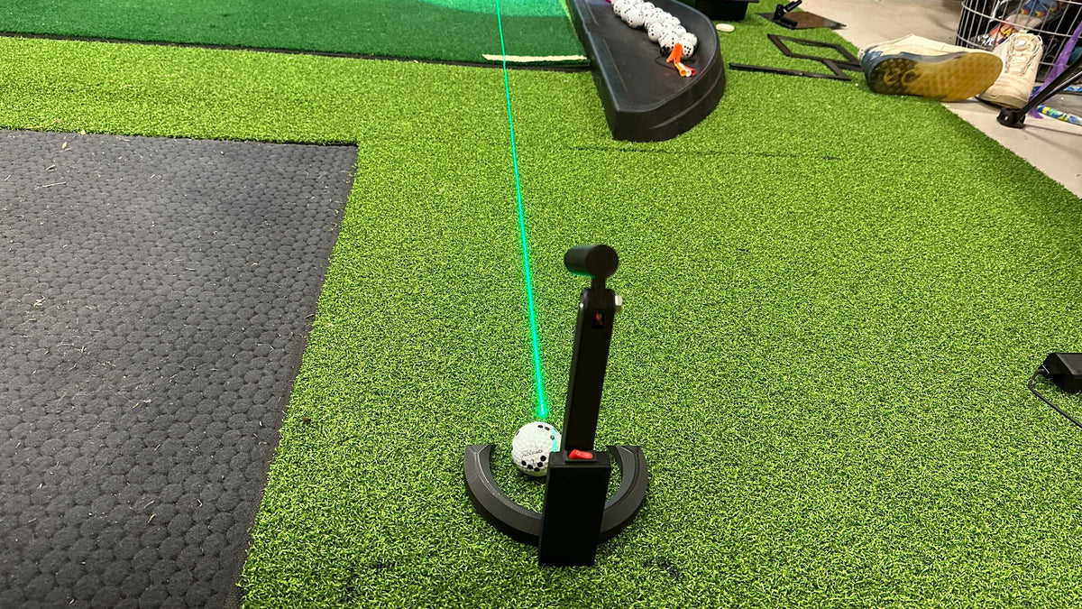 Laser alignment and putting tool shown from behind on a golf mat