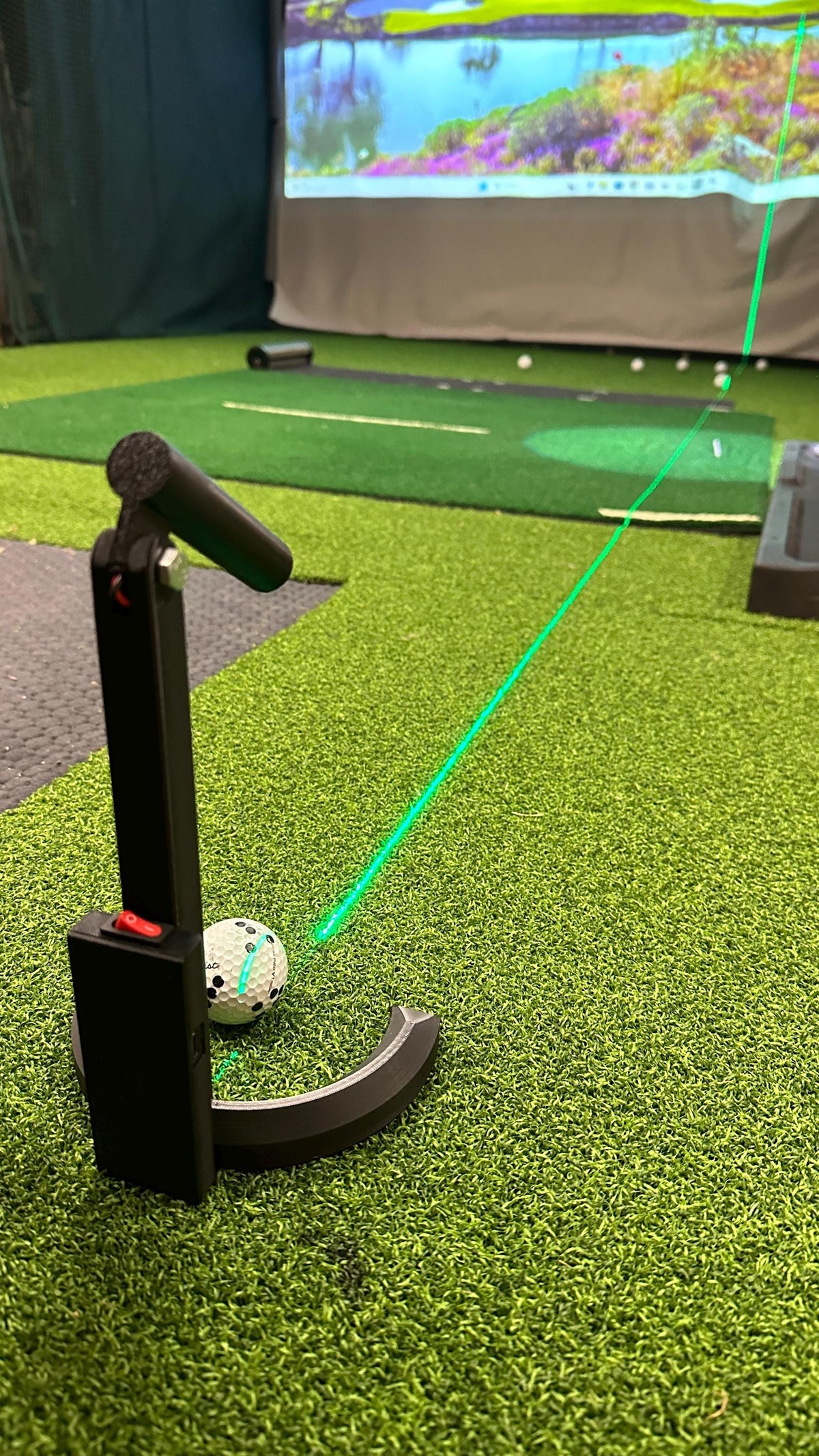 Laser alignment and putting aid projecting a green line toward the simulator screen
