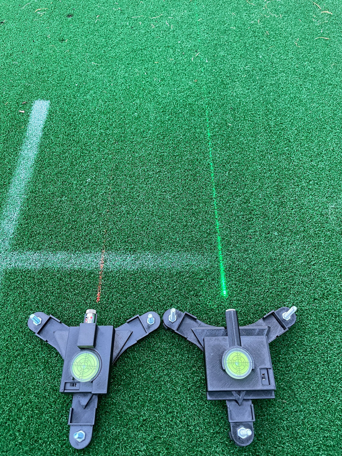 Red and green laser alignment lines projected onto an outdoor golf mat