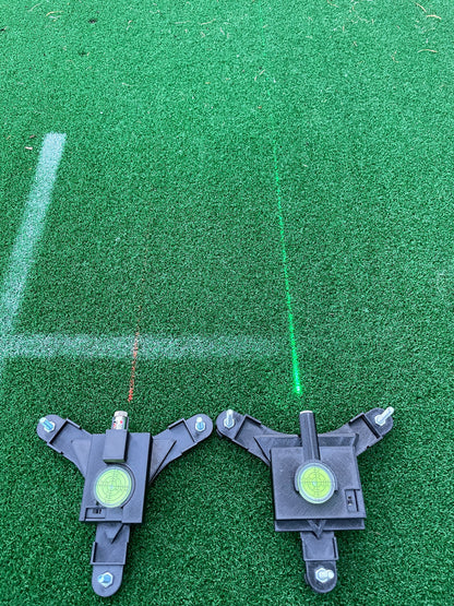 Red and green laser alignment lines projected onto an outdoor golf mat