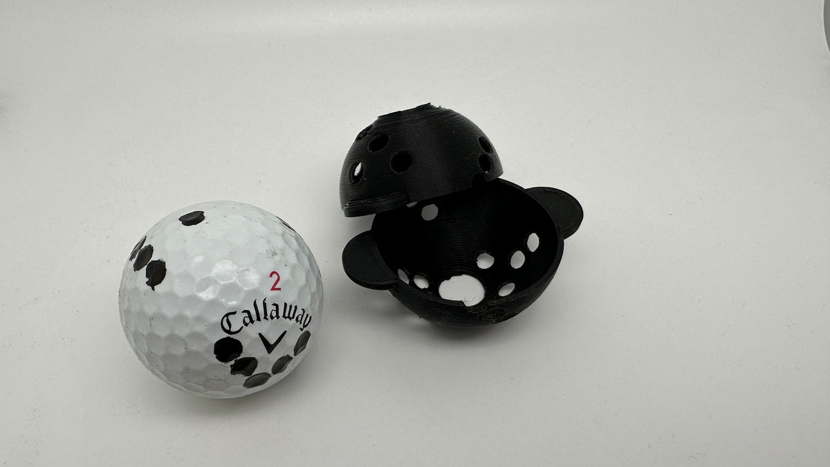 Marked golf ball beside the two halves of the Rapsodo MLM2PRO ball marker