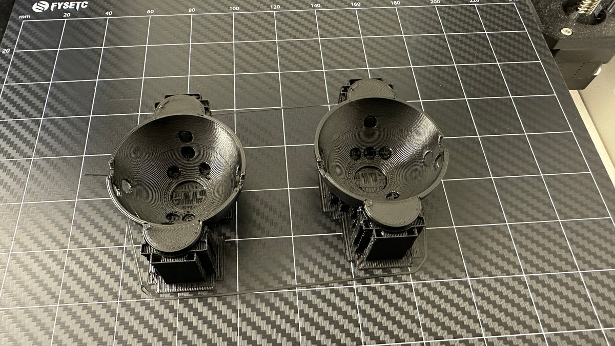 Two Rapsodo MLM2PRO ball marker halves on a 3D printer build plate